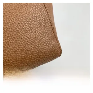 Close-up of brown litchi grain leather texture and precise stitching on the tote bag