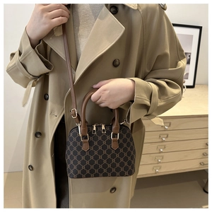 Classic dark brown printed shell bag with leather handles shown in a lifestyle setting