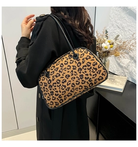 Close-up of leopard print Boston bag with black leather trim worn by a model in a stylish setting