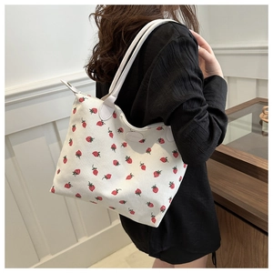 Detail of strawberry print tote bag with corduroy texture and white leather handles