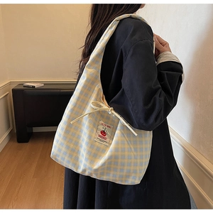 Detailed view of canvas tote bag with yellow and blue plaid and cherry embroidery