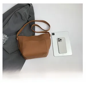Brown lychee grain leather bucket bag size comparison with tablet and smartphone