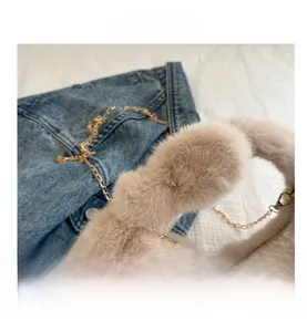 Détail du sac à main en peluche beige avec chaîne dorée et poignées circulaires