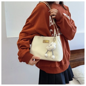 Detail of white corduroy tote bag with brown leather logo tag and cloud plush charm