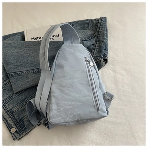 Detail of light blue wrinkled nylon chest bag with vertical metal zipper and buckle