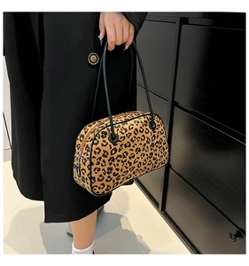 Detailed view of the leopard print handbag with a sleek black zipper and stylish metal rings