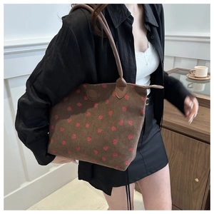 Close-up of strawberry print on brown corduroy tote bag with round leather logo detail