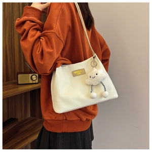 Detail of white waffle texture shoulder bag with cute cloud charm and brown leather label