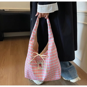 Detail view of handmade blue checkered tote bag with ribbon bow and cherry label