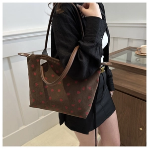 Detail of strawberry print on brown corduroy tote bag with durable leather handle
