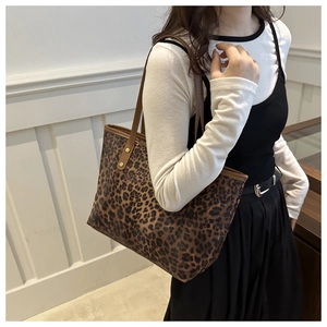 Detailed close-up of leopard print tote bag with brown leather straps and gold rivets