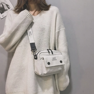 Detailed view of white canvas crossbody bag with adjustable strap and brand logo