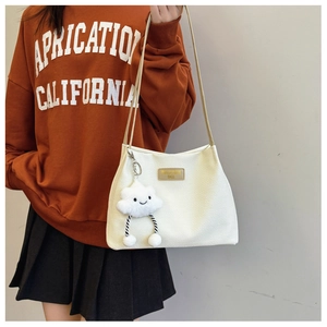 Detail of white waffle texture tote bag with cloud charm on model wearing orange sweatshirt