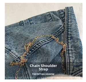 Détail du sac en jean avec bandoulière en chaîne dorée et texture du tissu denim