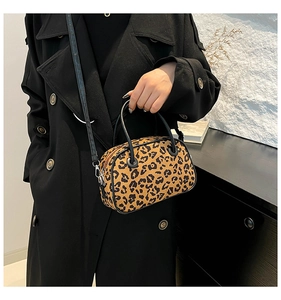 Detail shot of leopard print handbag with black leather handles on a female model