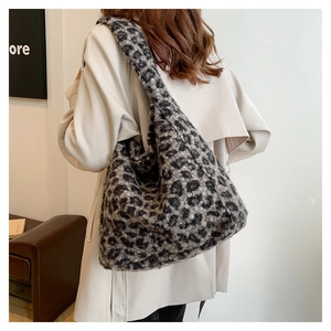 Leopard print plush tote bag shown on model wearing beige coat in a minimalist interior
