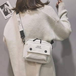 Detailed back view of off-white canvas crossbody bag with DCY logo and wide shoulder strap