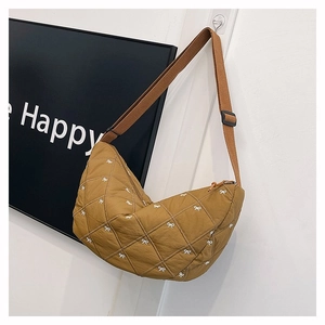 Detail der khakifarbenen Stepptasche mit weißen Bogenschleifen und verstellbarem Gurt