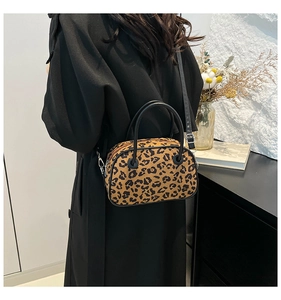 Fashionable leopard print handbag with black handles worn by a model in a cozy interior