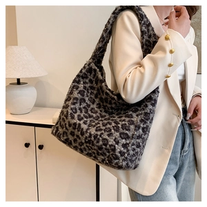 Detailed view of large leopard print plush tote bag worn over the shoulder by a model