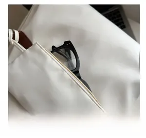 Close-up of white nylon pouch charm with zipper showing glasses storage detail