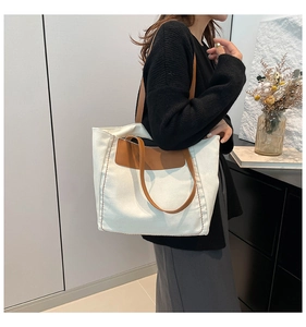 Model showing a large white canvas tote bag with brown leather handles and stitching