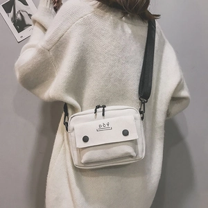 Detailed shot of a beige canvas crossbody bag with black straps and DCY logo for students
