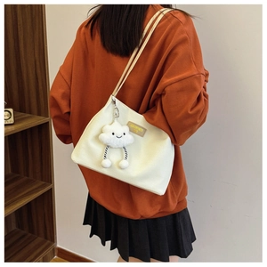 White corduroy tote bag with cloud pendant shown on model in a casual lifestyle setting