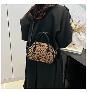 Detail view of leopard print handbag with black handles and metal strap buckles