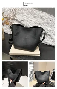 Detail of black pebbled leather texture and wide shoulder strap on tote bucket bag