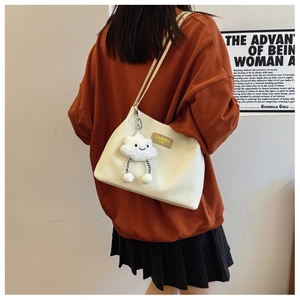 Detail view of white waffle knit tote bag featuring a cute cloud plush charm and leather logo