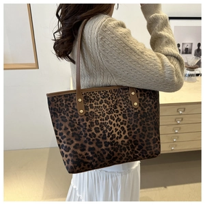 Detail of leopard print tote bag with brown leather handle and gold rivet reinforcement