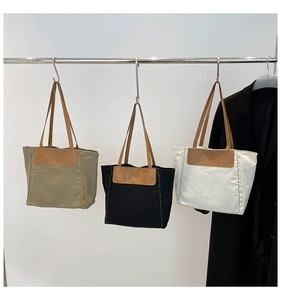 Three canvas tote bags in khaki, black, and white with brown leather straps and contrast stitching