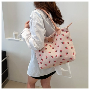 Detailed texture of pink corduroy tote bag with strawberry embroidery and leather strap