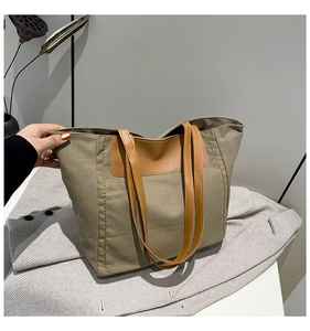 Close-up of khaki canvas tote bag with brown leather handles on grey herringbone blazer