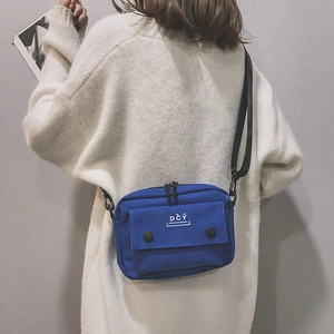 Detail of blue canvas messenger bag showing metal zippers and DCY printed front pocket