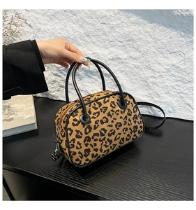 Detail of leopard print boston bag featuring black round handles and silver hardware hooks