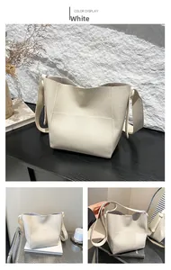 Detail of cream white lychee leather bucket bag with wide strap and minimalist design