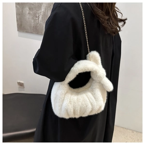 Détail du sac bandoulière en fausse fourrure crème avec chaîne dorée et texture nuage