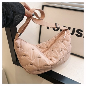 Detail der rosa gesteppten Halbmondtasche mit Bogenstickerei und breitem Gurt