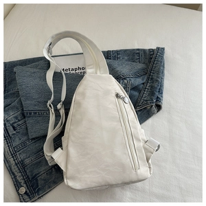Detailed view of white washed texture chest bag on denim jacket showing fabric and zippers