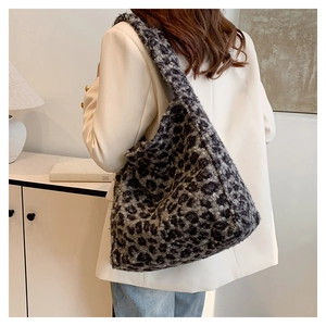 Detail view of the plush leopard print tote bag on a model wearing a white suit