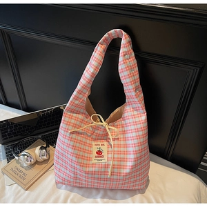 Detail of blue plaid canvas tote bag with cherry patch on white bedding background