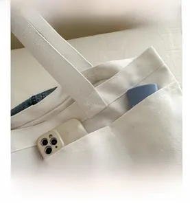 Detail view of large canvas tote bag showing side pocket with smartphone for storage
