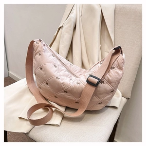 Rosafarbene gesteppte Tasche mit Schleifenstickerei auf einem hellen Stuhl liegend