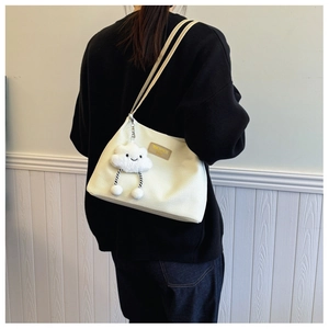 Detail of waffle-textured cream tote bag with leather logo and cloud plush charm