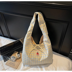 Detail of yellow and blue plaid canvas tote bag with cherry patch and laptop as prop