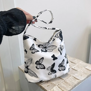Détail du sac cabas en toile avec motifs de papillons noirs sur fond blanc épuré