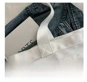 Detailed close-up of reinforced cross-stitching on durable white canvas tote bag handle