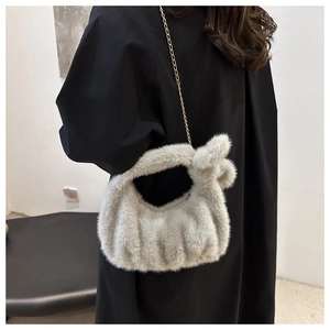 Détail du sac à main en fausse fourrure gris clair avec poignée nouée et chaîne dorée